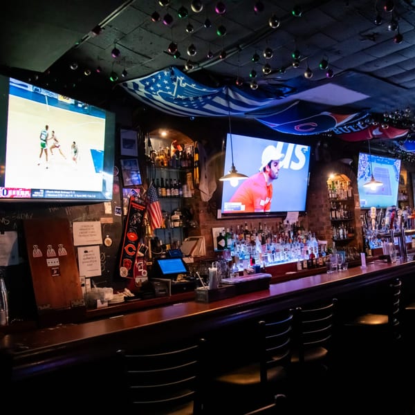 The Overlook sports bar interior with multiple TVs showing sports, a fully stocked bar, and bar stools.