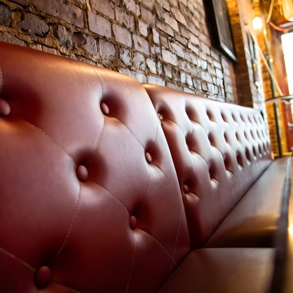 Tufted red leather booth seating against a rustic brick wall at Overlook sports bar.