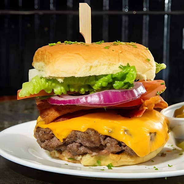 A tall Overlook burger with cheese, bacon, lettuce, tomato, onion, and a wooden skewer.