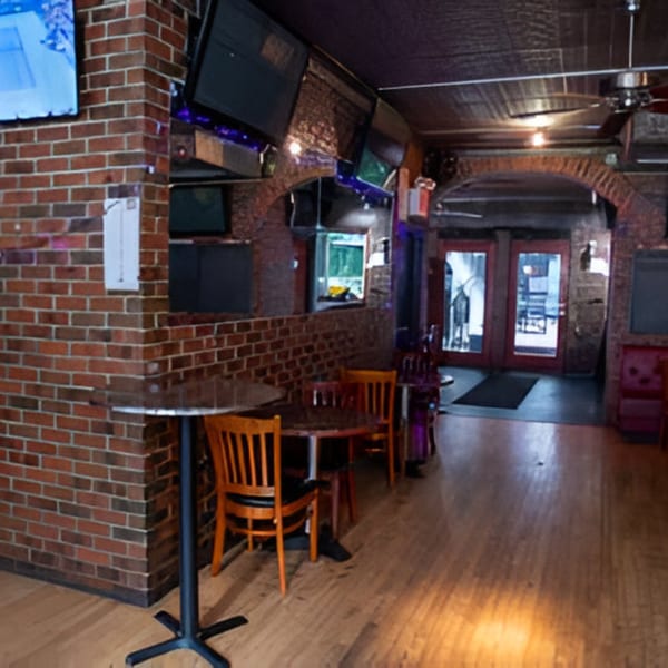 Interior of Overlook sports bar with brick walls, wooden tables, chairs, and multiple TVs.