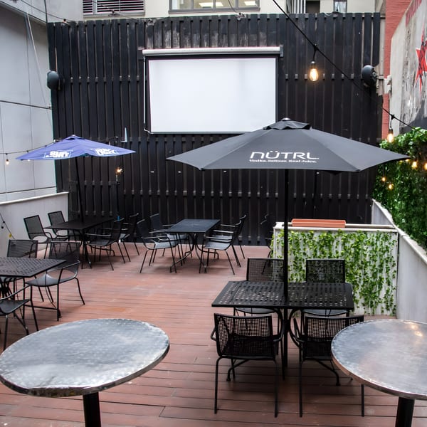 Overlook's outdoor patio with black tables and chairs, umbrellas, string lights, and a large projection screen.