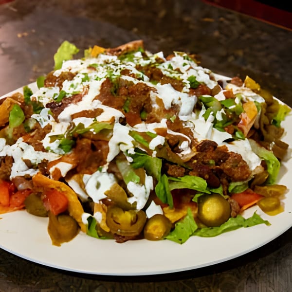 A plate of Overlook's loaded nachos with ground beef, cheese sauce, lettuce, tomatoes, and jalapeños.