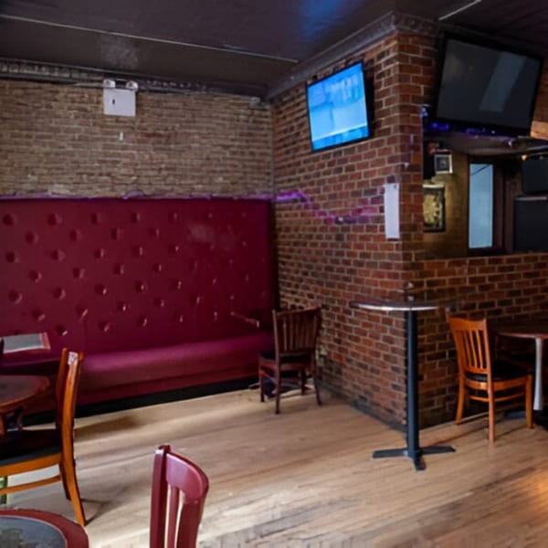 Overlook sports bar interior with brick walls, red booth seating, wooden chairs, and multiple TVs.