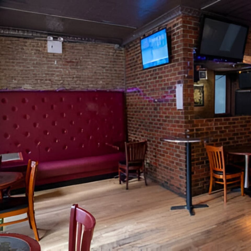 Overlook sports bar interior with brick walls, red booth seating, wooden chairs, and multiple TVs.
