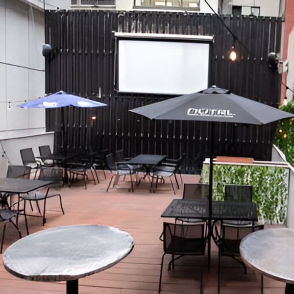 Overlook's outdoor patio with tables, chairs, umbrellas, and a large projection screen.