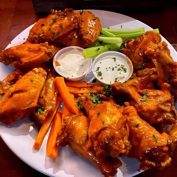 A large platter of Overlook's buffalo wings with celery sticks, carrot sticks, and two dipping sauces.
