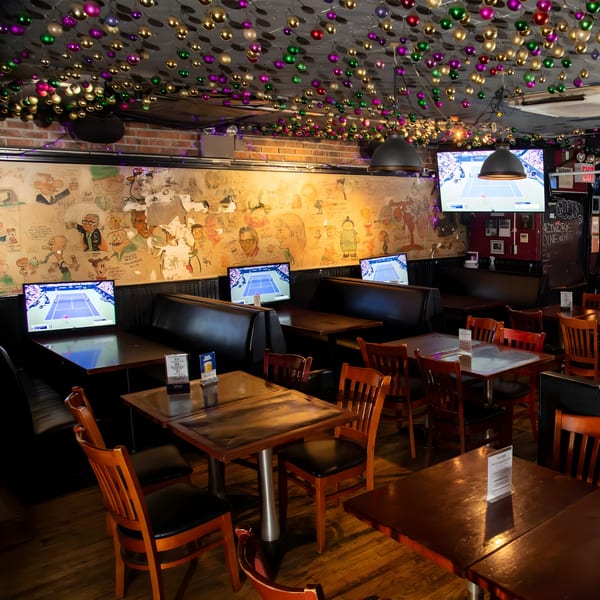 Interior of Overlook sports bar with multiple TVs showing tennis, booth seating, and festive ceiling decorations.